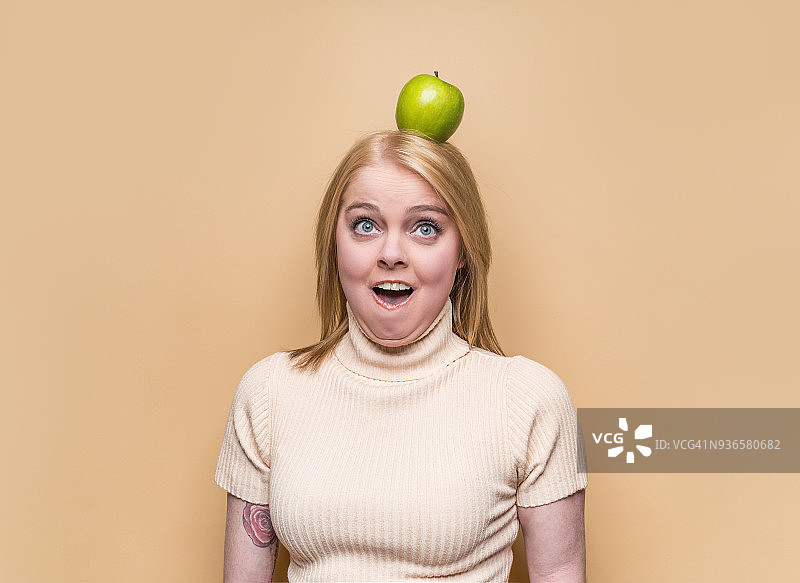 头顶绿色苹果的金发女人图片素材