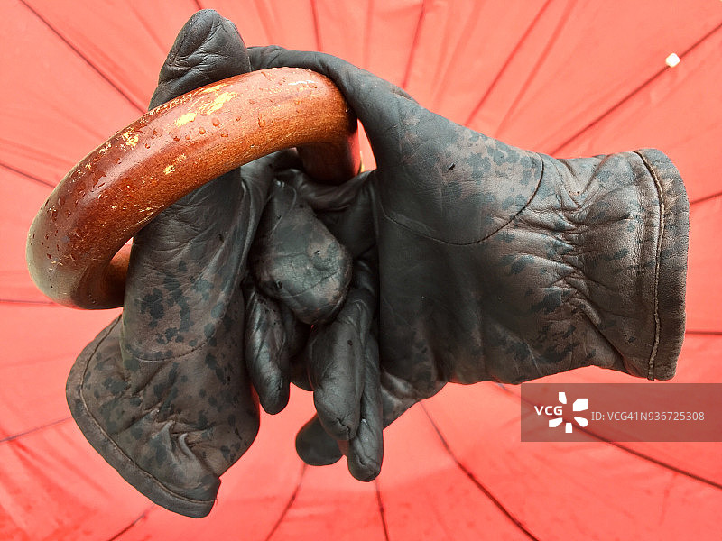 棕色皮手套握着红色雨伞的木柄图片素材