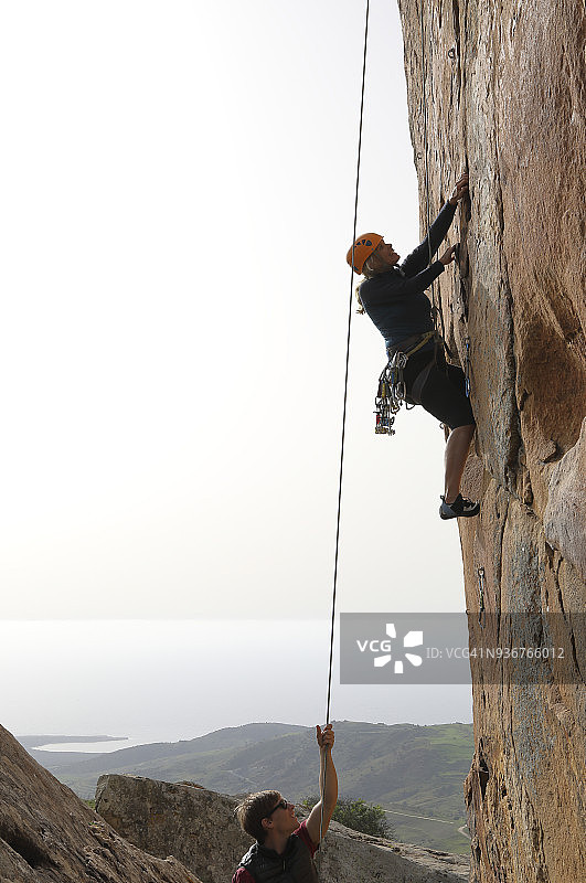 女人攀爬悬垂的岩壁，放置保护装置图片素材