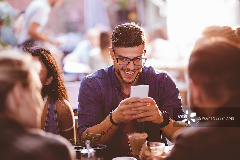 在咖啡店用手机发短信的快乐时尚男人图片素材