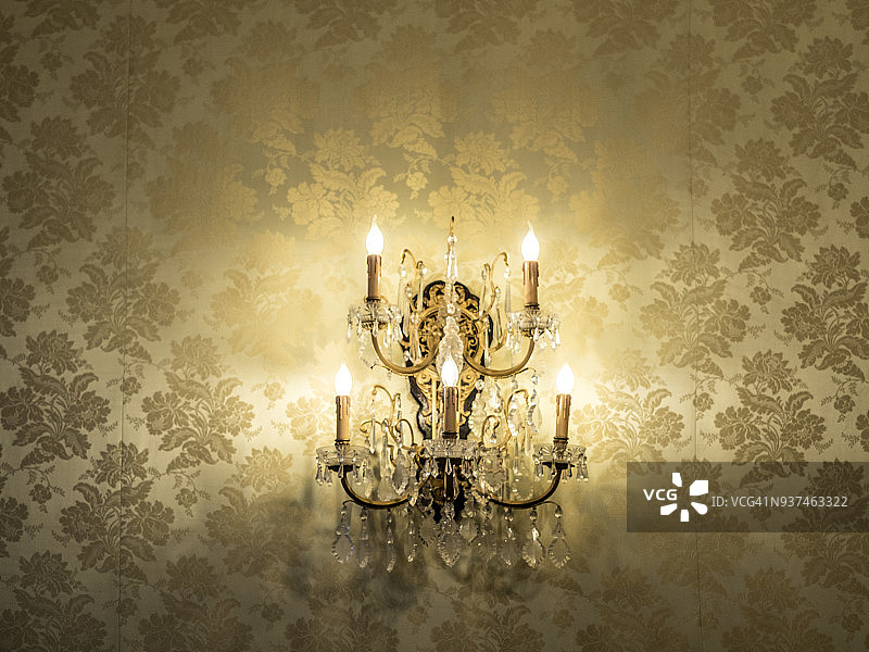 经典风格水晶壁灯特写，壁灯在贴有壁纸的墙壁上图片素材