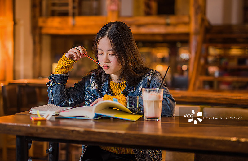 在咖啡馆学习的年轻亚洲女性图片素材