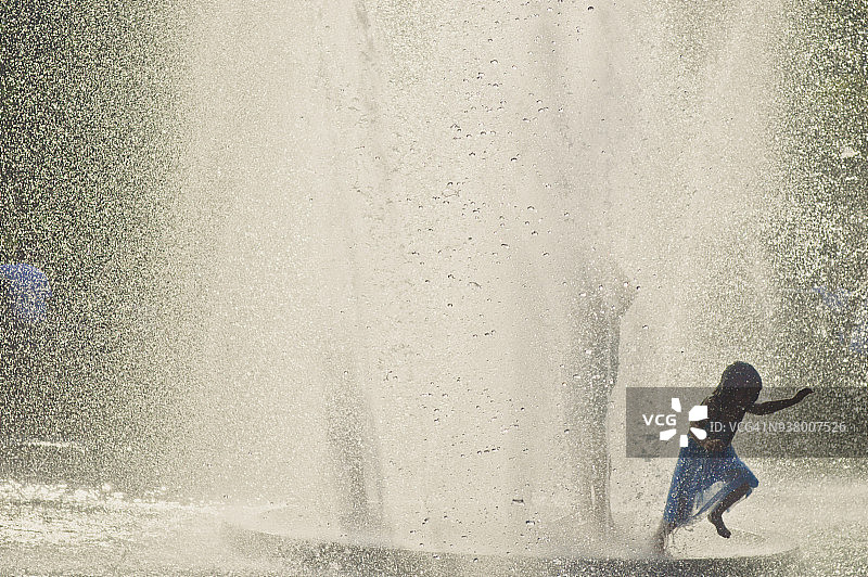 小女孩在公园喷泉中玩耍图片素材