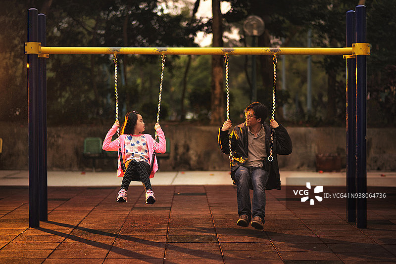 亚洲儿童和父亲坐在秋千上图片素材