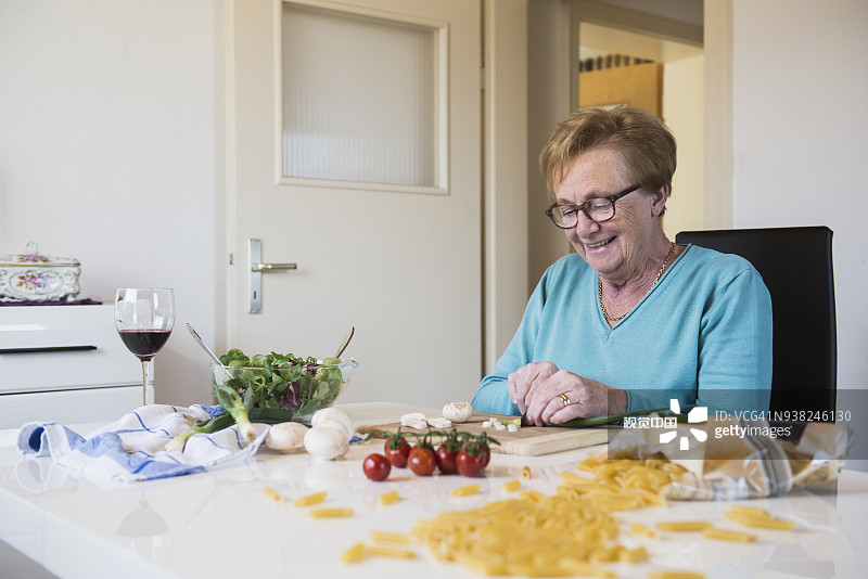 老婆婆在厨房餐桌上切葱图片素材