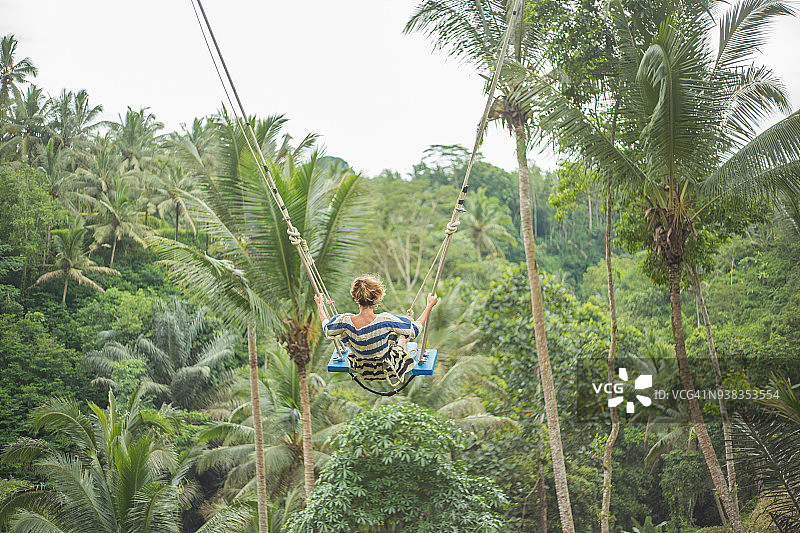 在巴厘岛丛林上荡秋千的年轻女子图片素材