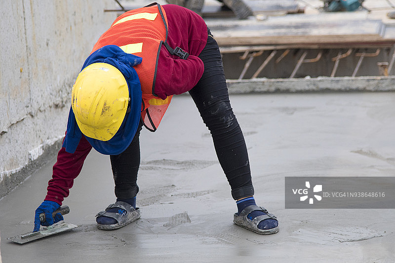 身穿安全标准制服的建筑工人在建筑工地浇筑商业混凝土地面图片素材
