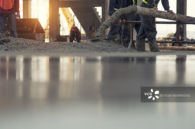 建筑工人：在建筑工地的商业混凝土楼层浇筑混凝土，土木工程师图片素材