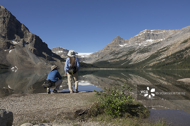 女人欣赏加拿大艾伯塔省班夫国家公园弓湖冰川的倒影图片素材