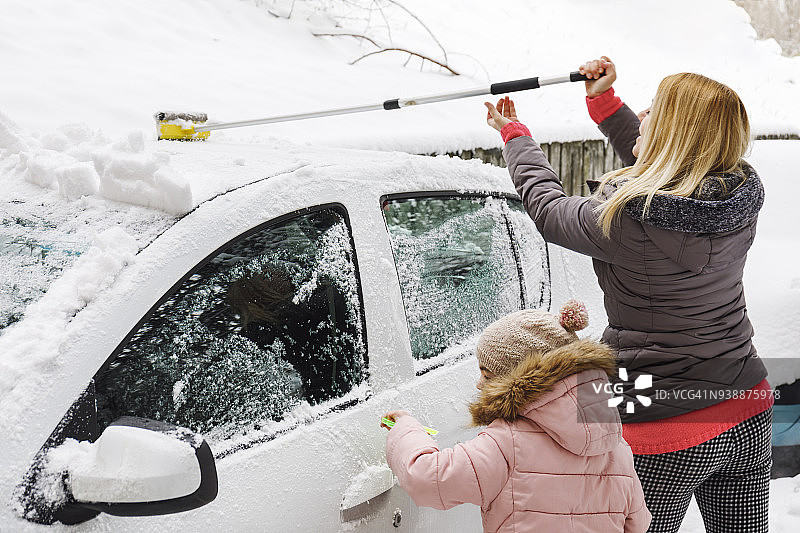一家人一起从汽车上清除积雪图片素材