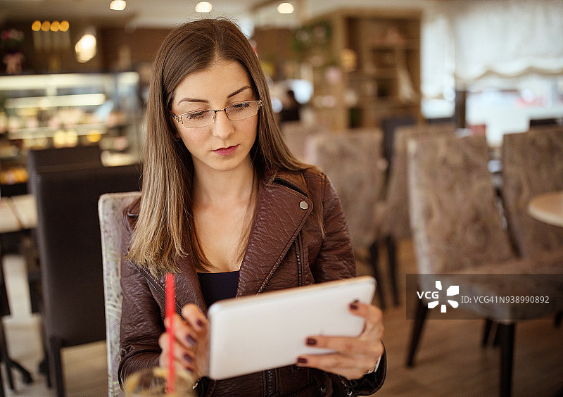 在咖啡馆使用平板电脑的年轻女人图片素材