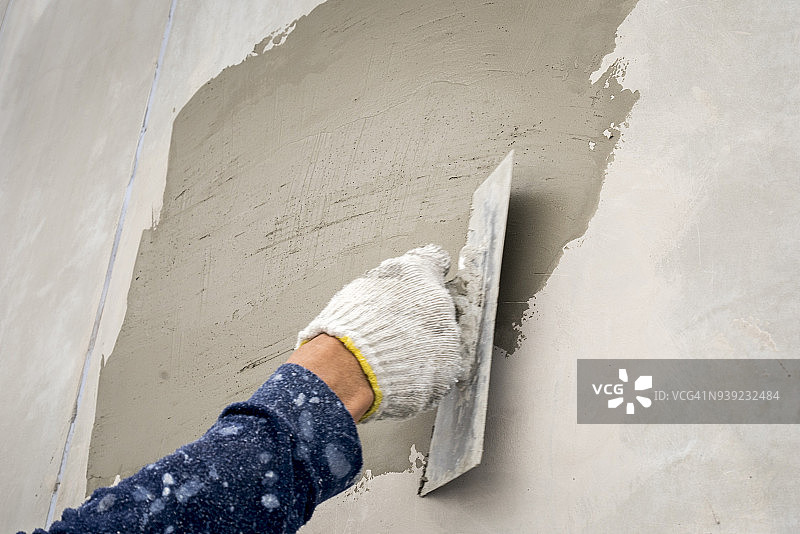 在阁楼墙上用手抹湿水泥灰泥的特写图片素材
