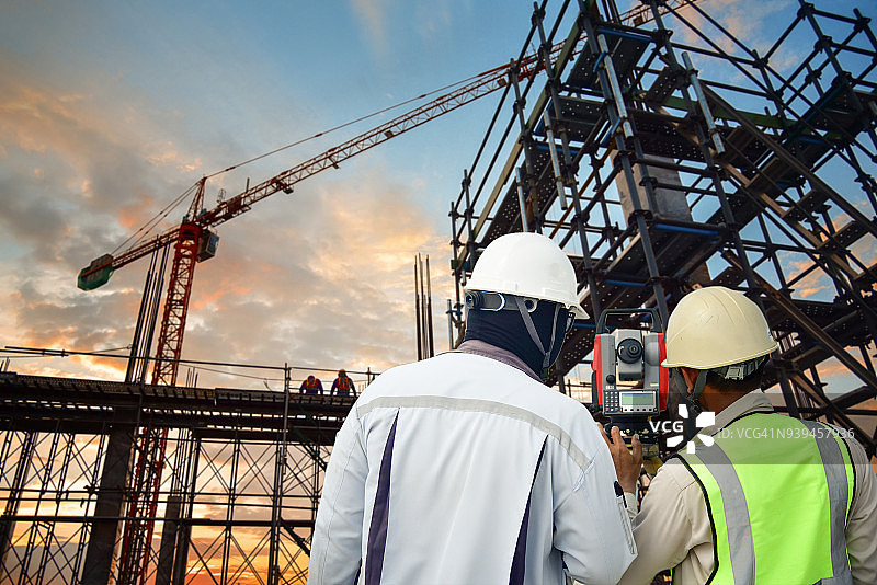 测量员、建筑工人、工程师在户外建筑工地使用经纬仪进行测量工作图片素材