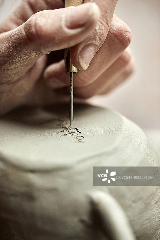 陶艺师在杯子上刻字特写图片素材