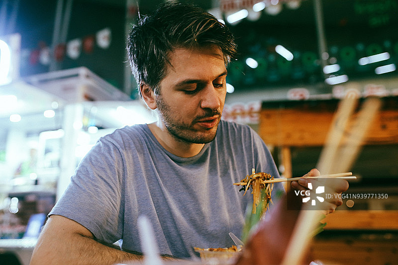 年轻男人在泰国曼谷街头市场吃正宗泰国菜图片素材