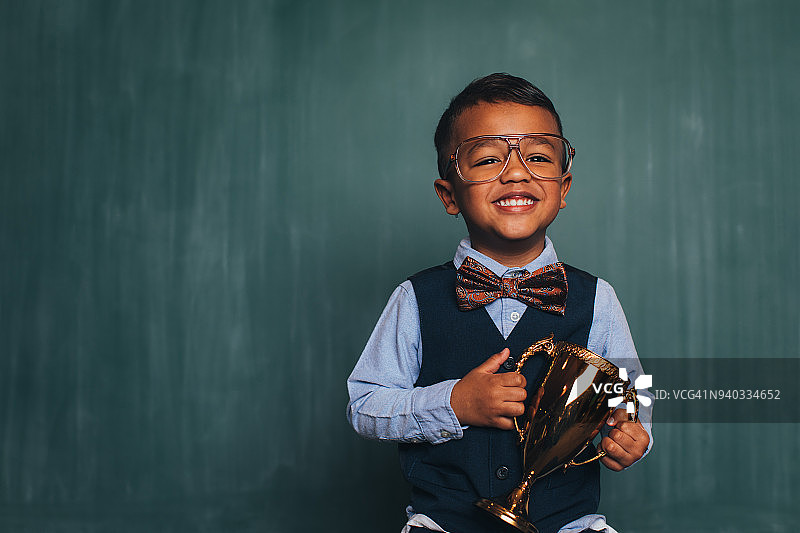 教室里拿着奖杯的复古书呆子男孩图片素材