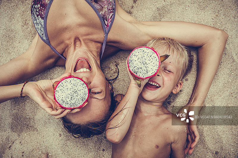 快乐的女人和男孩用火龙果当眼镜图片素材