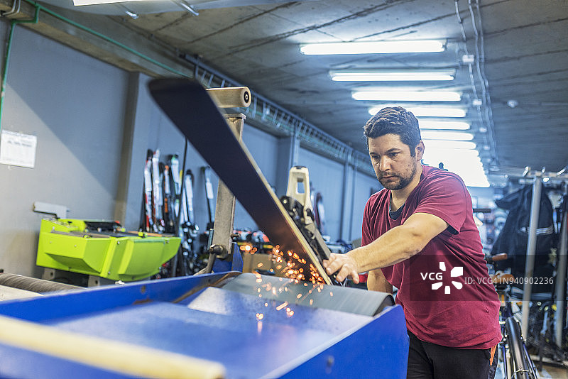 滑雪板调整与维修：冬季商店工人进行滑雪板底面维修图片素材