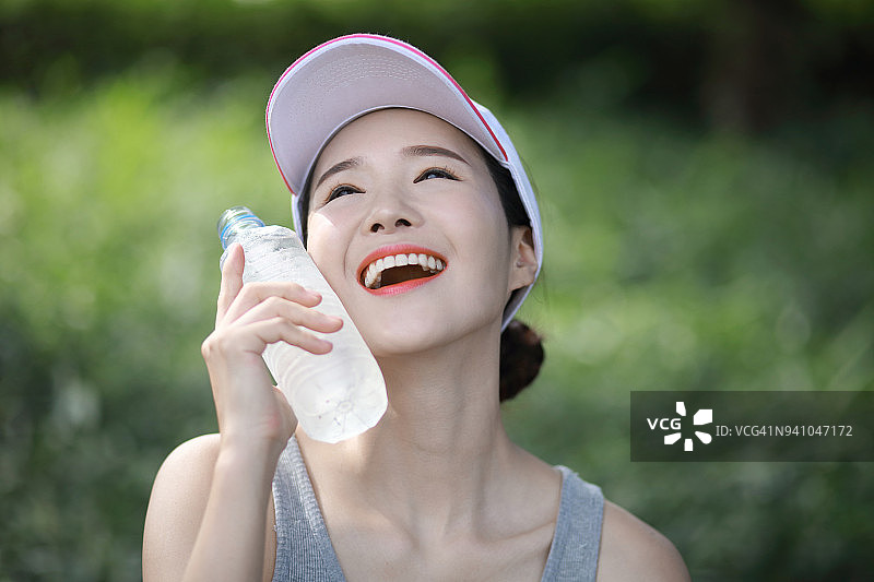 运动后用矿泉水瓶补充水分的年轻女人图片素材