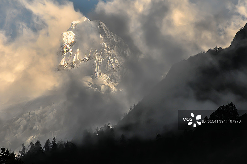 云层中的缝隙显露出海拔7118米高的Ganesh II峰，尼泊尔宗姆山谷图片素材