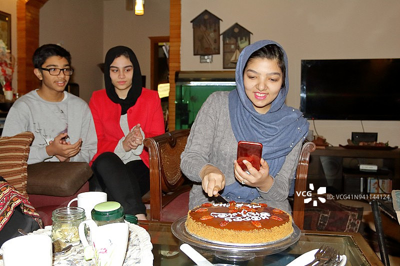 戴头巾的年轻女孩在手机视频通话中与朋友庆祝生日图片素材