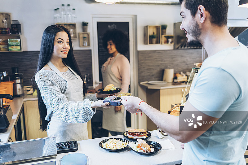 年轻男人在快餐店使用信用卡图片素材