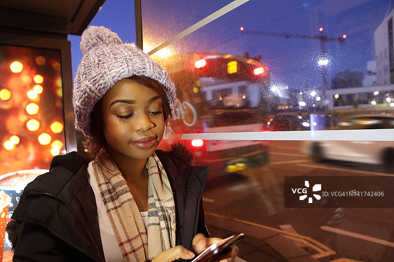 年轻女子夜晚在公共汽车站打电话图片素材