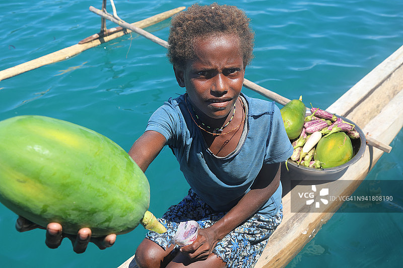 太平洋岛屿儿童在独木舟上卖水果图片素材