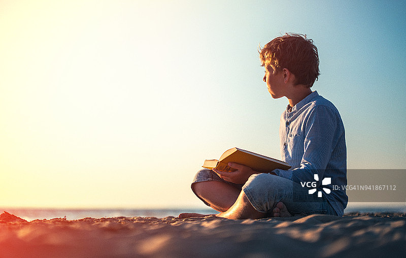 在日落时分的海滩上读书图片素材