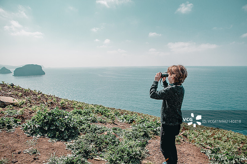 小男孩用双筒望远镜观察图片素材