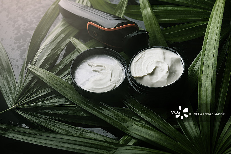 绿色树叶和潮湿背景上的电子剃须刀与剃须膏及须后水图片素材