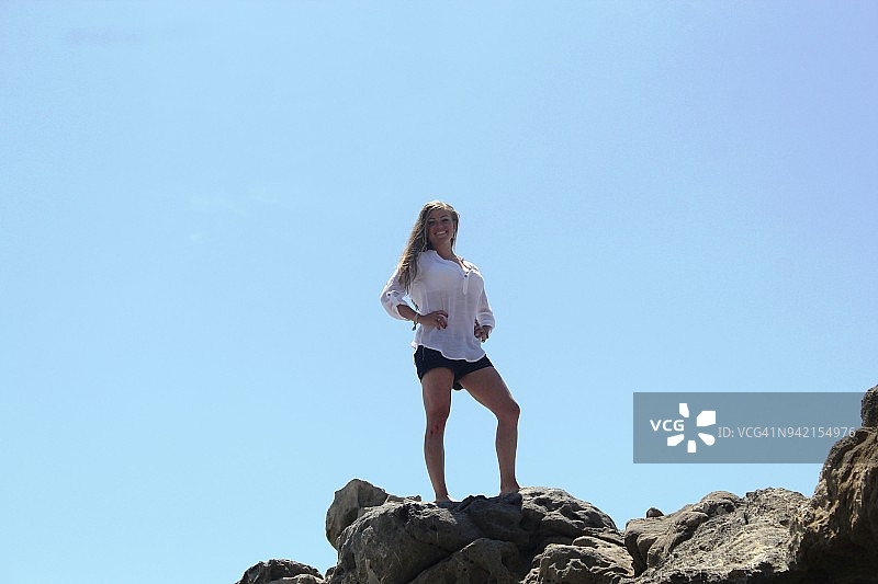 健美的女人站在马里布的岩石上图片素材