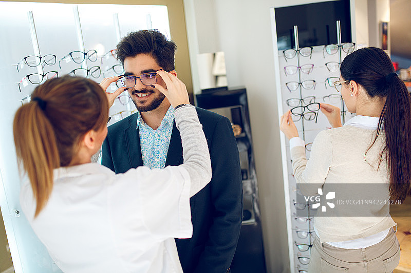 年轻男人在眼镜店挑选眼镜图片素材