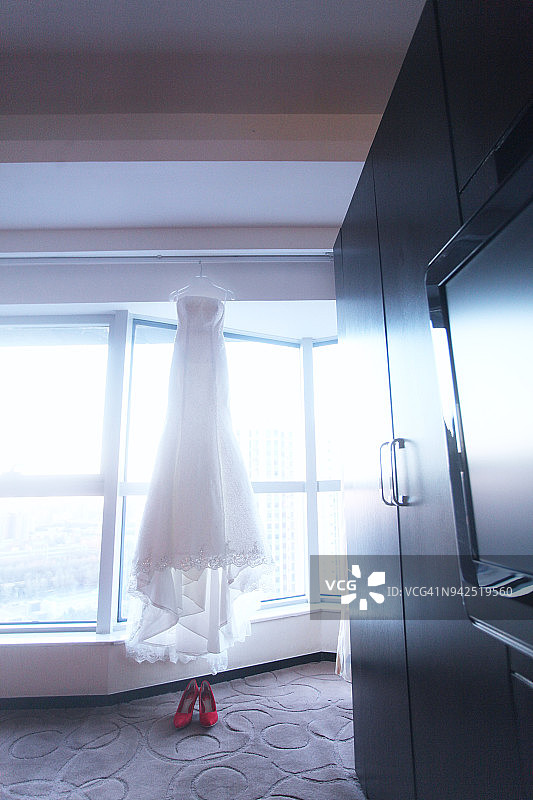 酒店房间里挂着的红色高跟鞋和白色婚纱图片素材