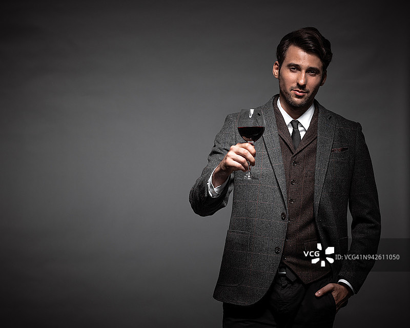 手持一杯葡萄酒的年轻帅气男子图片素材