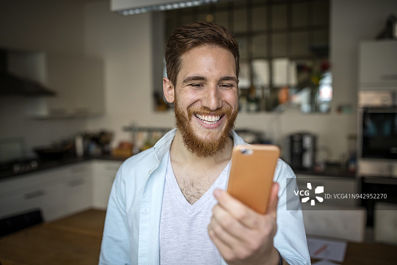在厨房使用手机的年轻创意胡须男图片素材