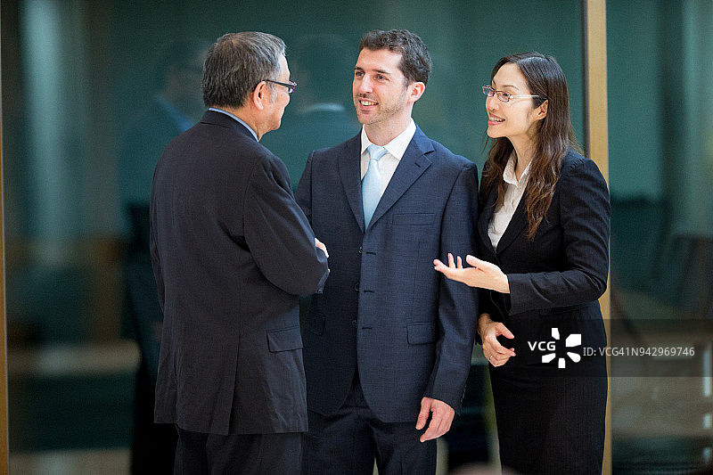 白人商人与他的翻译讨论与年长亚洲商人的交易图片素材