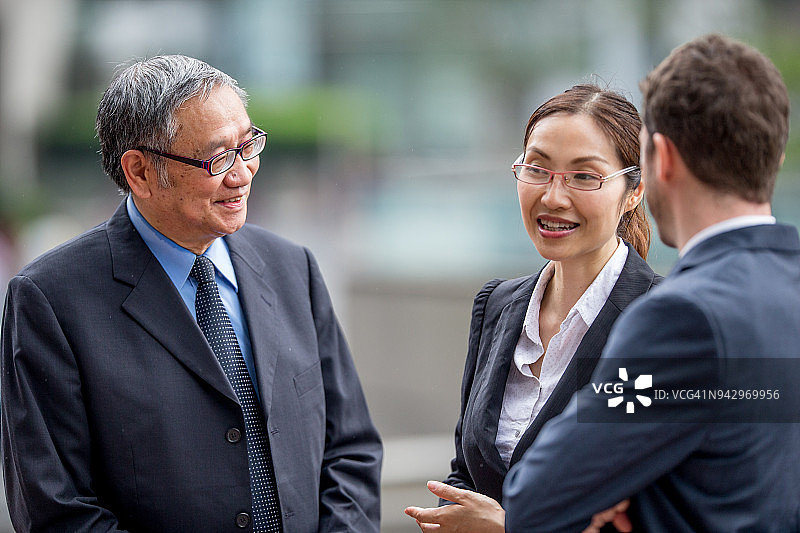 与翻译讨论与亚洲资深商人交易的白人商人图片素材