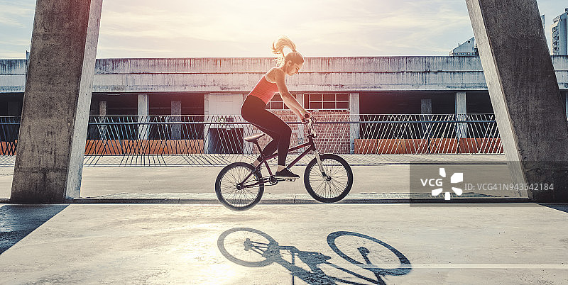 年轻女子骑着平地花式小轮车图片素材