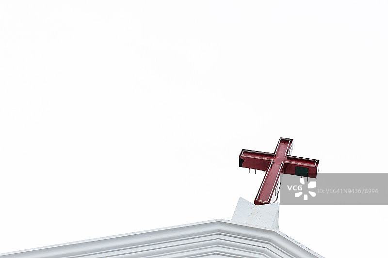 教堂塔楼上红色的十字架，白色天空为背景图片素材