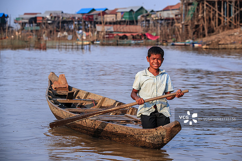 在柬埔寨洞里萨湖上划船的柬埔寨男孩图片素材
