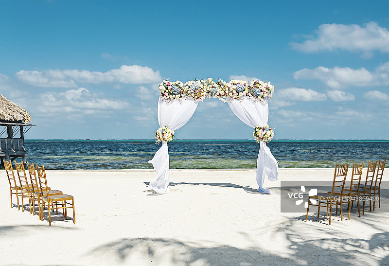 海滩上的鲜花拱门与八把椅子，适合小型海滩婚礼图片素材