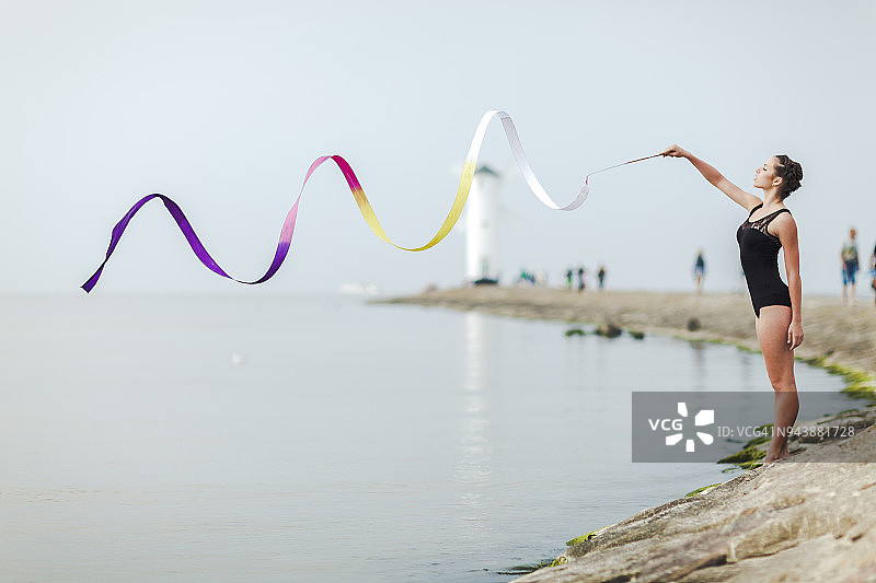 在海边户外用彩带训练的女子体操运动员图片素材