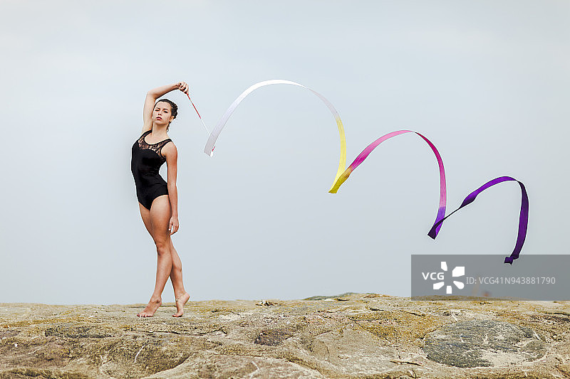 在海边户外用彩带训练的女子体操运动员图片素材