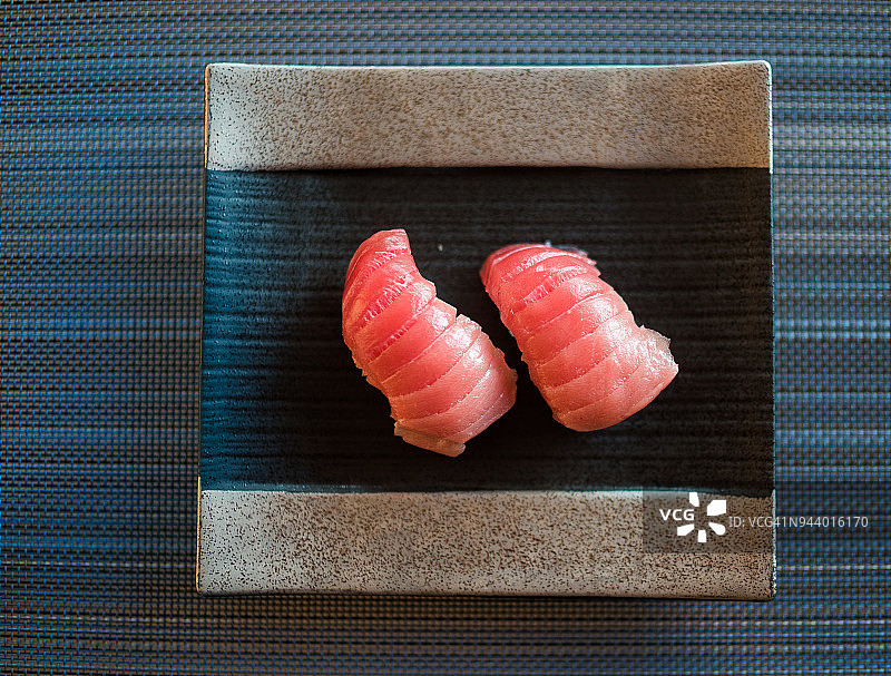两块中脂金枪鱼寿司，深色盘子图片素材