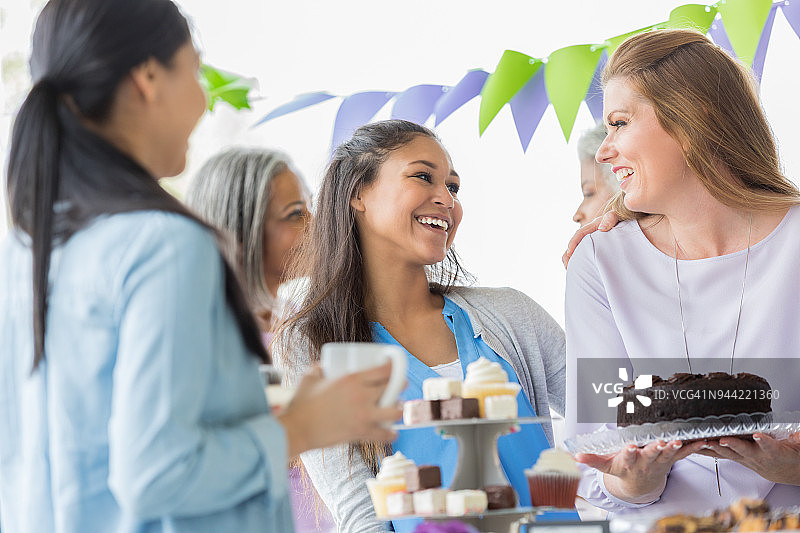 女性朋友在慈善活动中提供烘焙食品图片素材