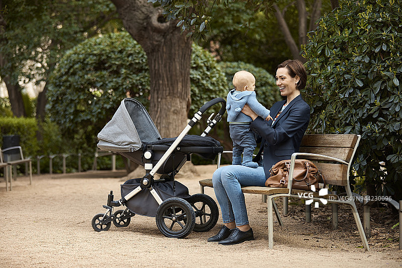 快乐的母亲和儿子坐在公园的长椅上图片素材