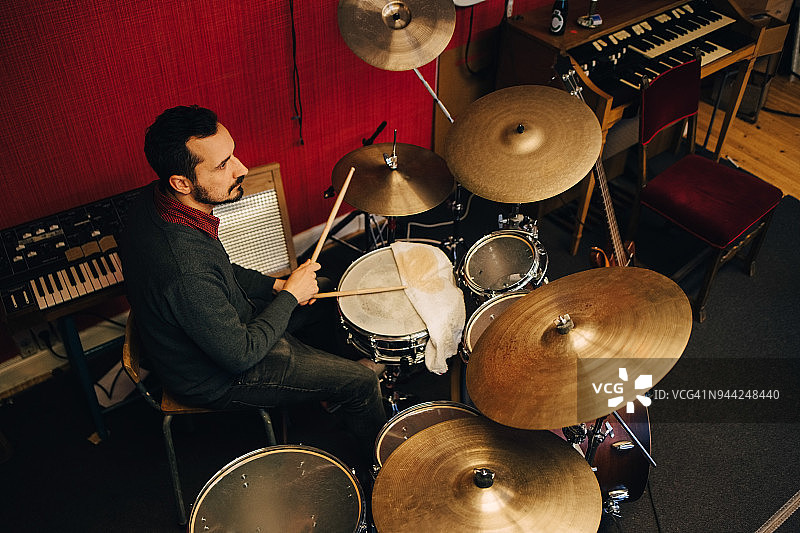 中年男人在录音室练习时演奏架子鼓图片素材