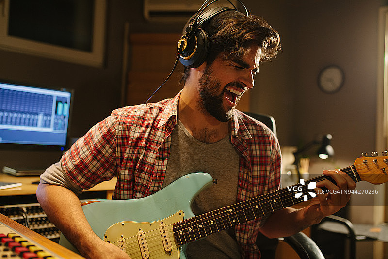 在音乐工作室弹吉他的有魅力的吉他手图片素材