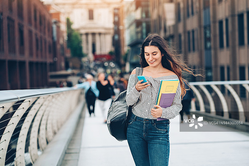 手持智能手机和教科书的大学生图片素材